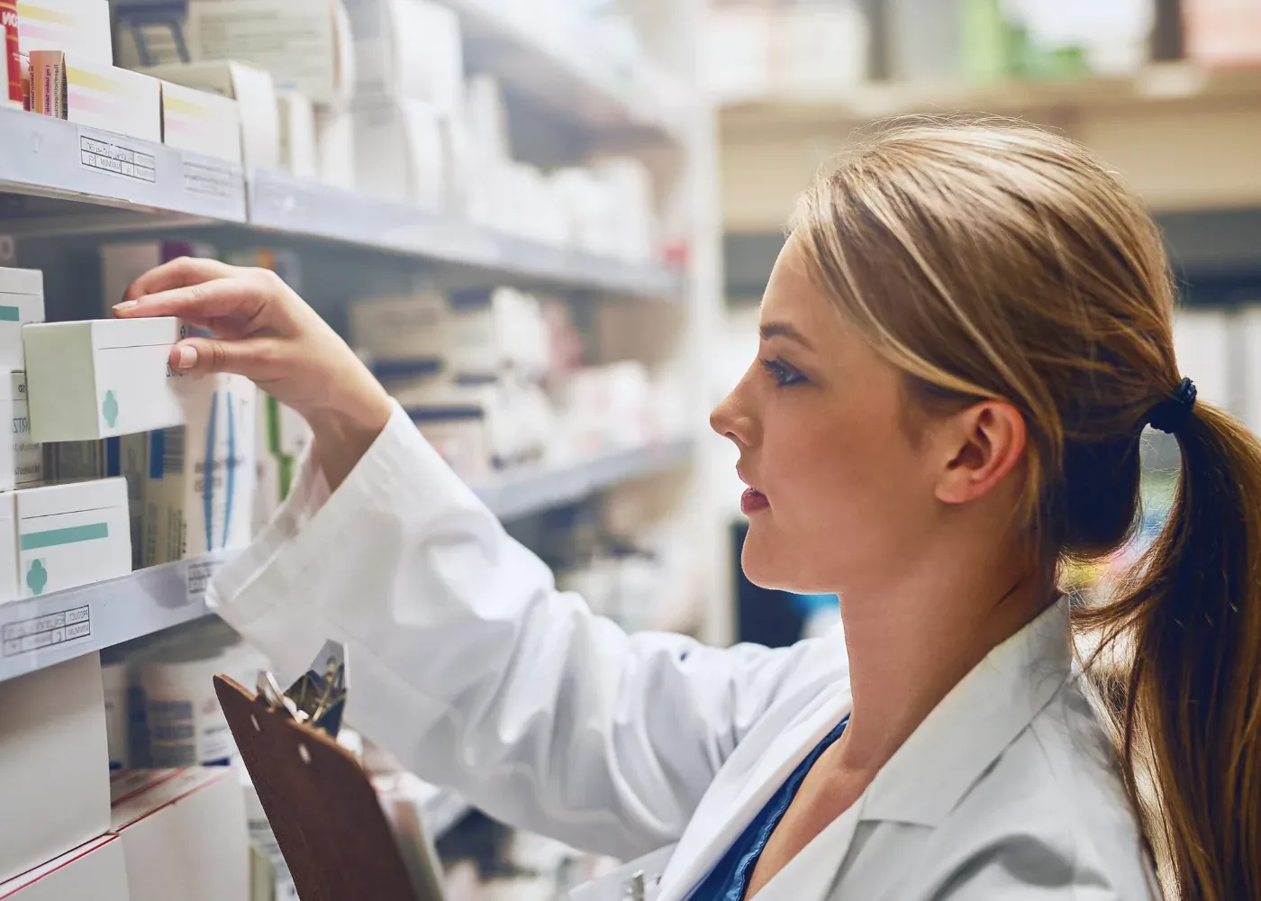 A pharmacist checking stock on a dispensary shelf